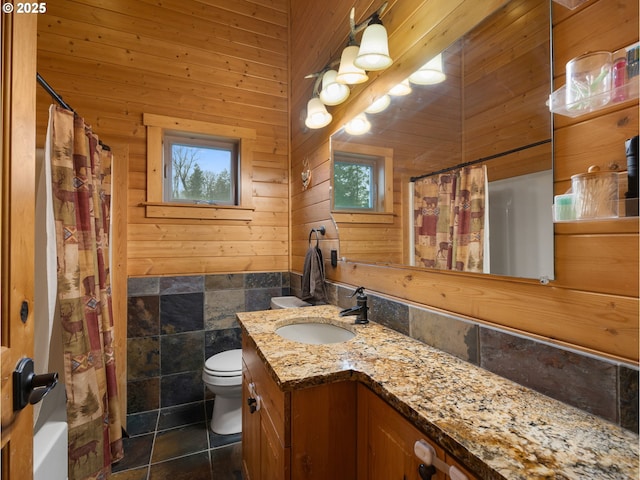 bathroom with curtained shower, toilet, wood walls, vanity, and tile patterned flooring