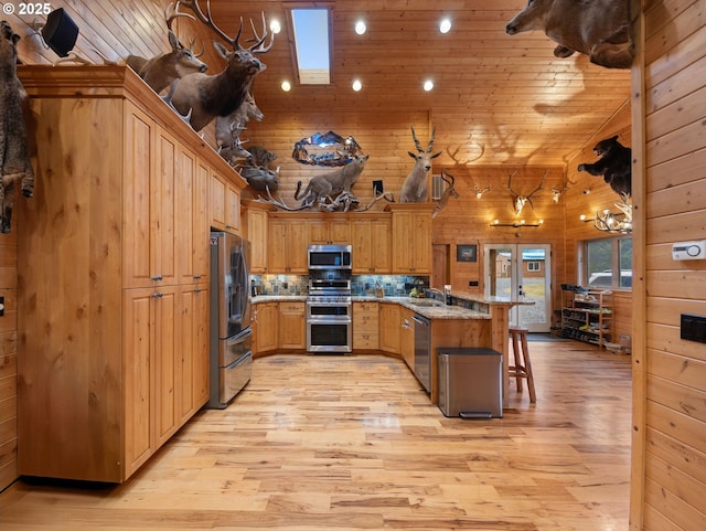 kitchen with wooden walls, wooden ceiling, appliances with stainless steel finishes, a breakfast bar area, and a peninsula