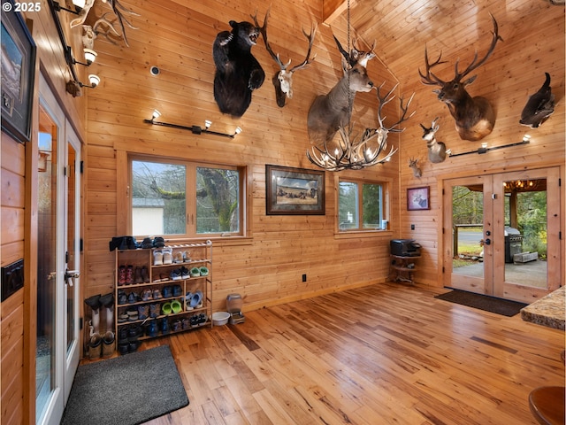 exercise area with high vaulted ceiling, a healthy amount of sunlight, wood walls, and wood finished floors