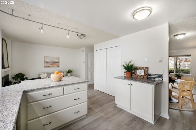 kitchen featuring light wood-type flooring, white cabinetry, and a textured ceiling