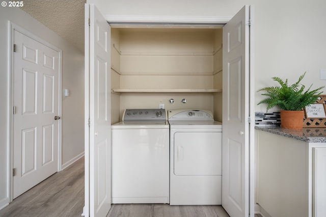 laundry area with a textured ceiling, light hardwood / wood-style flooring, and independent washer and dryer