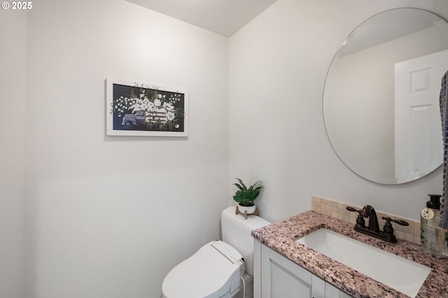 bathroom with toilet, vanity, and tasteful backsplash