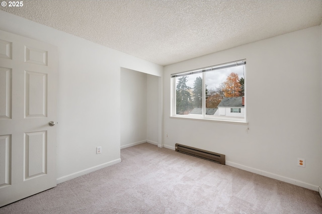 spare room featuring a textured ceiling, baseboard heating, and light colored carpet