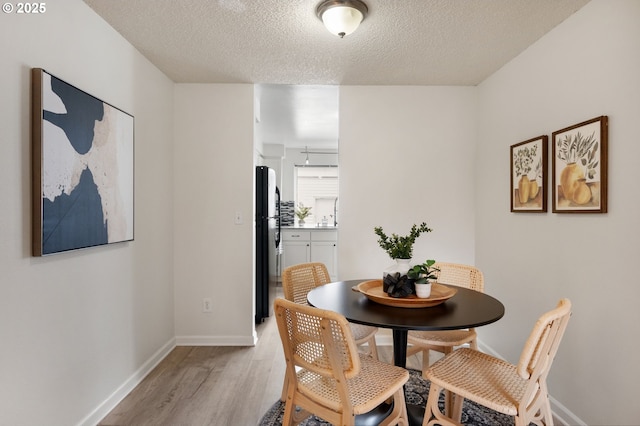 dining space with a textured ceiling and light hardwood / wood-style flooring