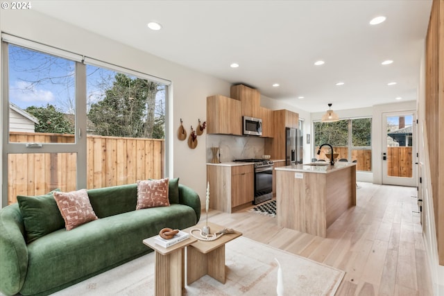 living room featuring plenty of natural light, sink, and light wood-type flooring