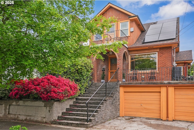 view of front of house with roof mounted solar panels, stairway, brick siding, and a balcony