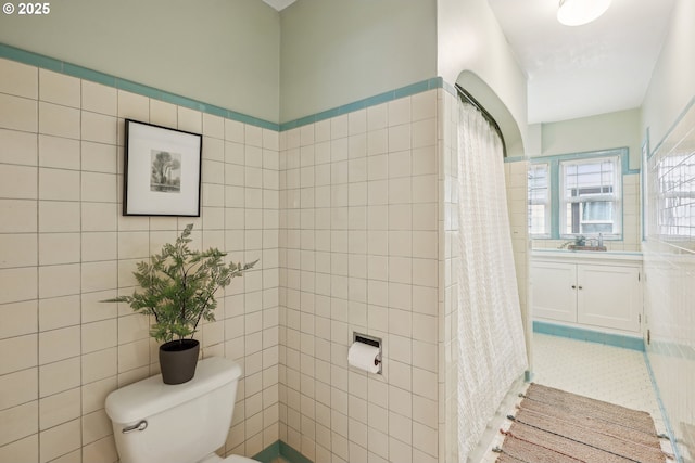full bath with toilet, a shower with curtain, tile walls, and vanity