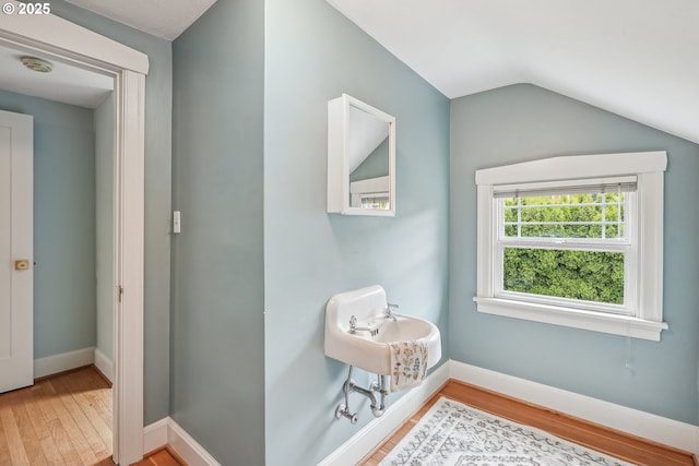 bathroom featuring baseboards, wood finished floors, and vaulted ceiling