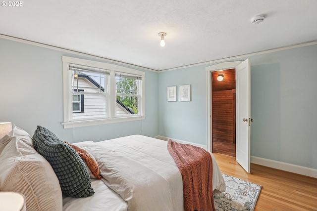 bedroom featuring a closet, baseboards, crown molding, and wood finished floors