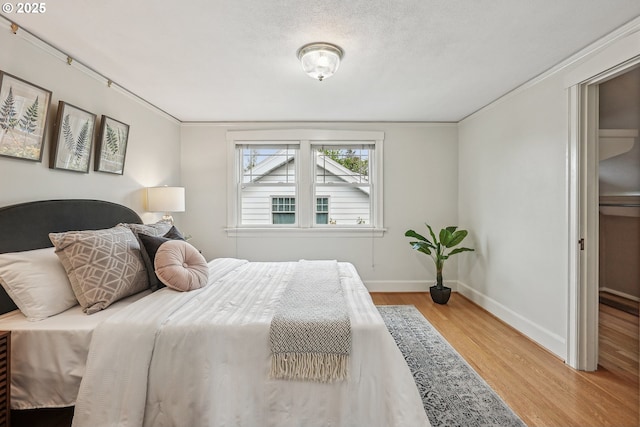 bedroom with baseboards, ornamental molding, and wood finished floors