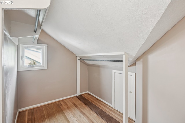 bonus room featuring baseboards, wood finished floors, and vaulted ceiling
