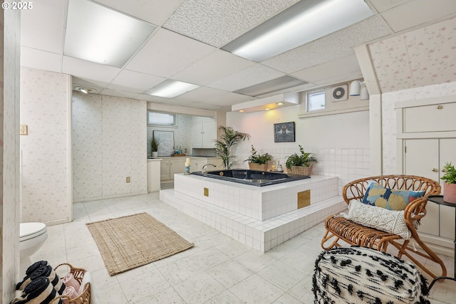 interior space featuring a drop ceiling and wallpapered walls