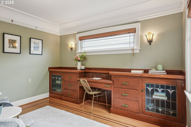 office with crown molding, baseboards, light wood-type flooring, and built in study area