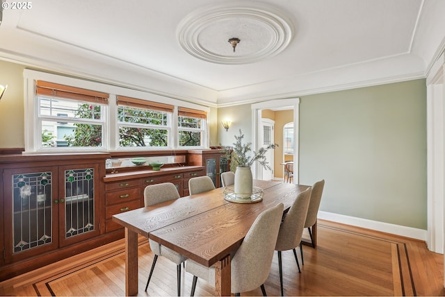 dining space with light wood-style floors, baseboards, and ornamental molding