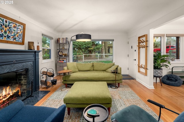 living room featuring a wealth of natural light, baseboards, a fireplace with flush hearth, and wood finished floors