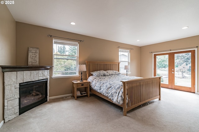 carpeted bedroom with access to outside, french doors, baseboards, a stone fireplace, and recessed lighting