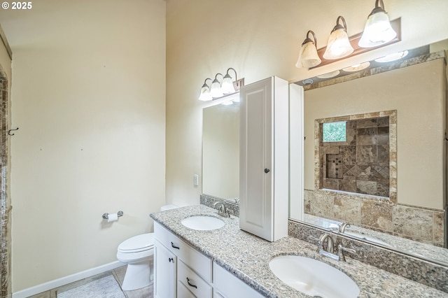 bathroom featuring toilet, double vanity, and baseboards