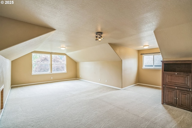 additional living space with light carpet, baseboards, a textured ceiling, and vaulted ceiling