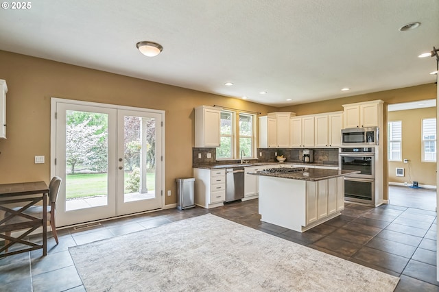 kitchen featuring stainless steel appliances, french doors, backsplash, white cabinetry, and a sink