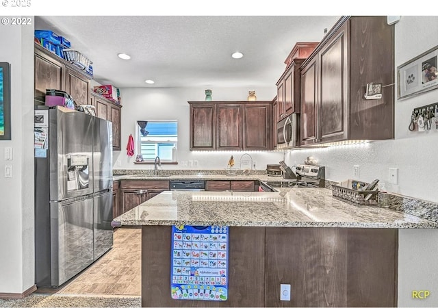 10387 N Mohawk Ave, Portland, OR 97203 - kitchen featuring stainless steel appliances, light stone countertops, a peninsula, dark brown cabinetry, and a sink