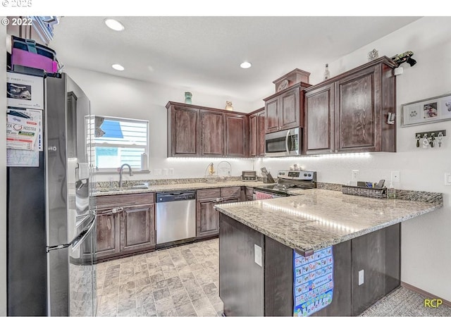 10387 N Mohawk Ave, Portland, OR 97203 - kitchen featuring stainless steel appliances, a sink, a peninsula, light stone countertops, and dark brown cabinets