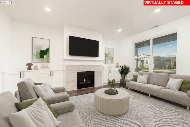 living room with a tiled fireplace and hardwood / wood-style flooring