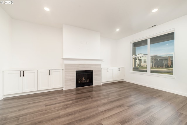 unfurnished living room with hardwood / wood-style floors and a tile fireplace