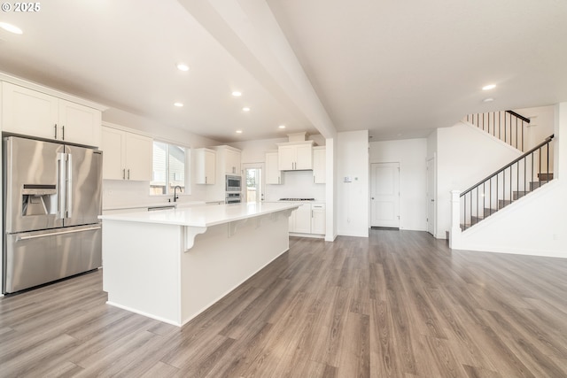 kitchen with white cabinetry, light hardwood / wood-style flooring, a kitchen island, stainless steel appliances, and decorative backsplash