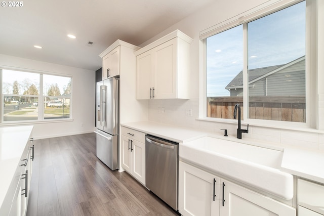 kitchen with sink, white cabinetry, plenty of natural light, hardwood / wood-style flooring, and stainless steel appliances