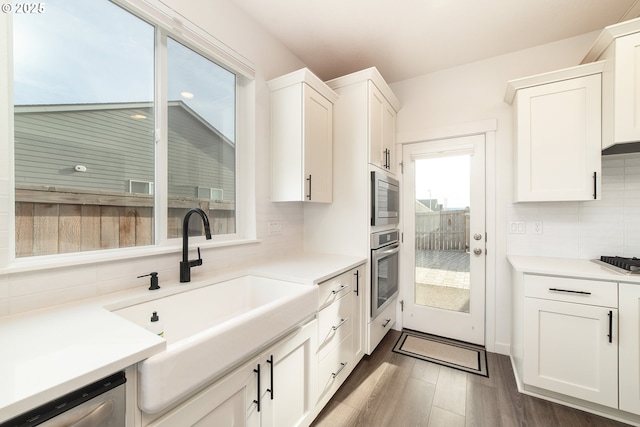 kitchen with dark wood-type flooring, sink, white cabinetry, appliances with stainless steel finishes, and backsplash