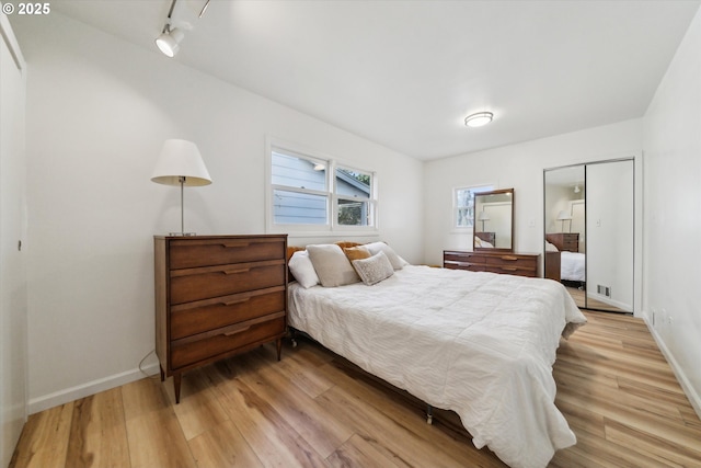 bedroom featuring baseboards, track lighting, and light wood-style floors