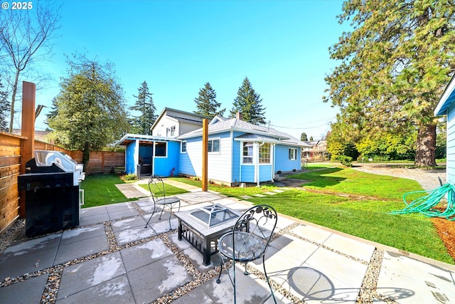 rear view of house featuring a fire pit, a yard, fence, an outdoor structure, and a patio area