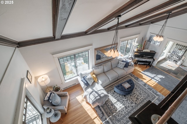 living area with a notable chandelier, wood finished floors, and beamed ceiling