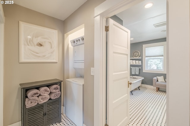 bathroom featuring recessed lighting, baseboards, a freestanding bath, and stacked washer and clothes dryer