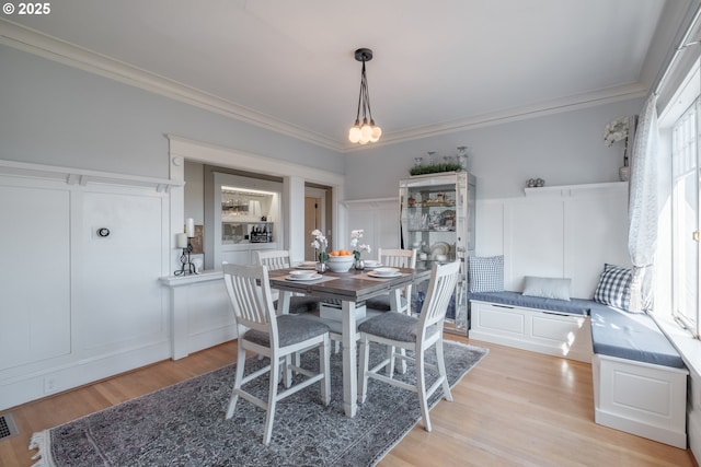 dining area featuring light wood-type flooring, visible vents, and crown molding