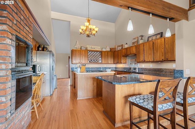 kitchen featuring a center island, oven, light wood-style flooring, brown cabinets, and high vaulted ceiling