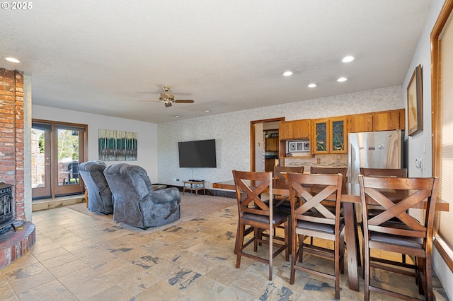 dining space with french doors, recessed lighting, wallpapered walls, ceiling fan, and a wood stove