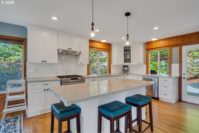 1626 NE Regatta Way, Lincoln City, OR 97367 - kitchen featuring stainless steel appliances, under cabinet range hood, a breakfast bar, decorative backsplash, and recessed lighting
