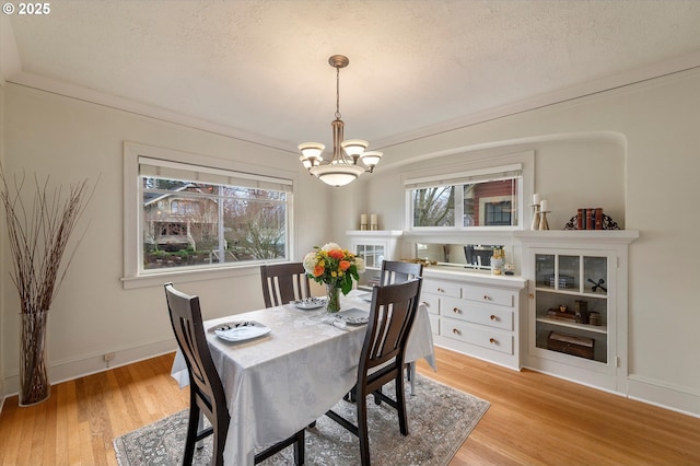 dining room with light wood-type flooring, baseboards, a textured ceiling, and a chandelier