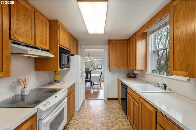 kitchen featuring black appliances, light countertops, under cabinet range hood, and a sink