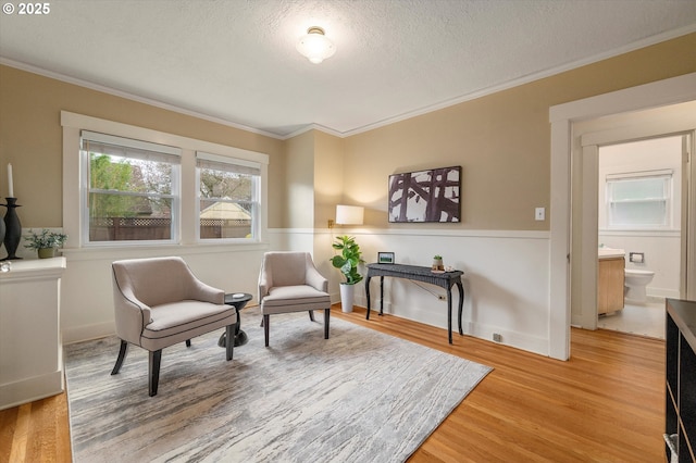 living area featuring light wood-style floors, crown molding, and a textured ceiling