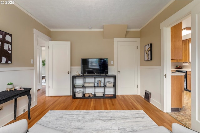 interior space featuring a wainscoted wall, light wood-type flooring, and ornamental molding