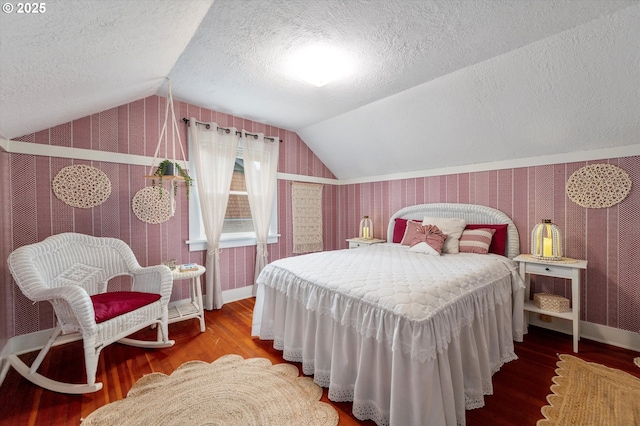 bedroom with lofted ceiling, a textured ceiling, wood finished floors, and wallpapered walls