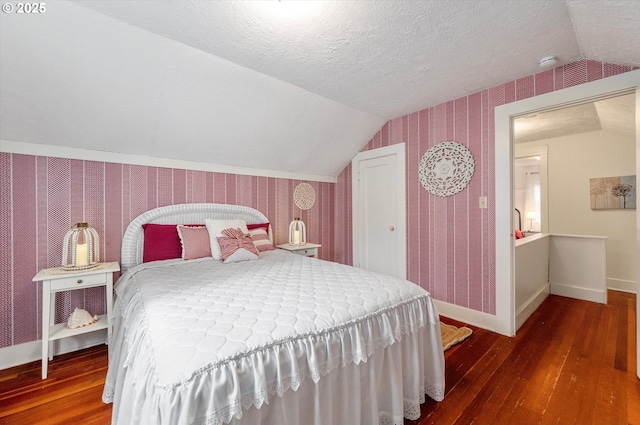 bedroom with a textured ceiling, wallpapered walls, lofted ceiling, and hardwood / wood-style floors