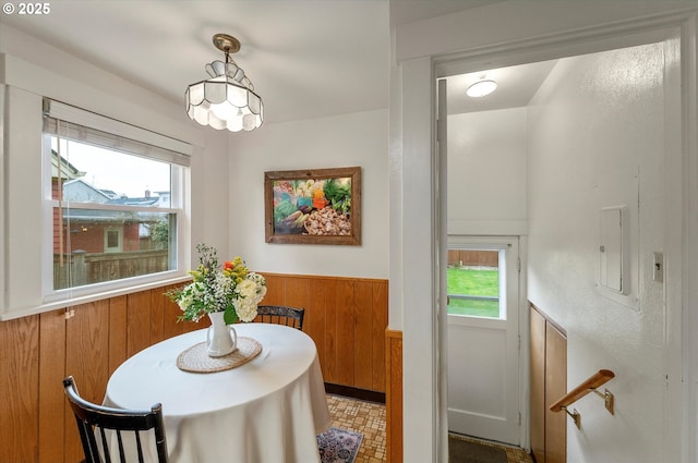 dining area featuring wooden walls, electric panel, and wainscoting