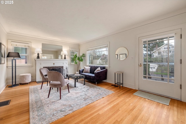 living room featuring visible vents, wood finished floors, a fireplace, and crown molding