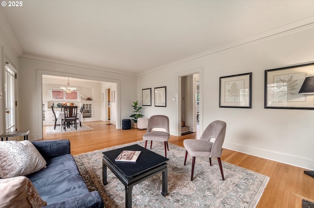 living area featuring baseboards, a notable chandelier, wood finished floors, and crown molding