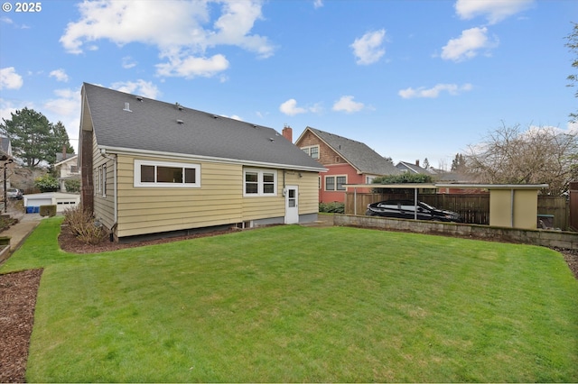 back of property with a yard, fence, and roof with shingles