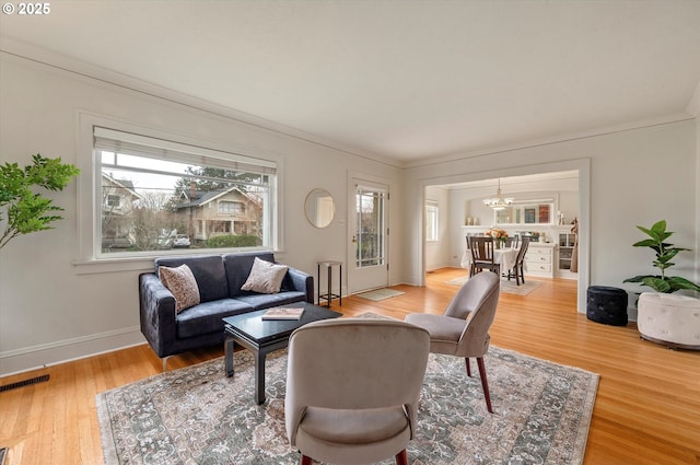 living area with visible vents, baseboards, an inviting chandelier, and light wood-style flooring