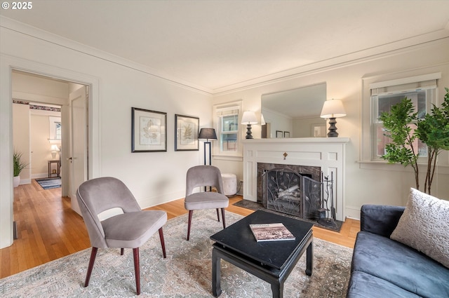 living room featuring wood finished floors, baseboards, a high end fireplace, and ornamental molding